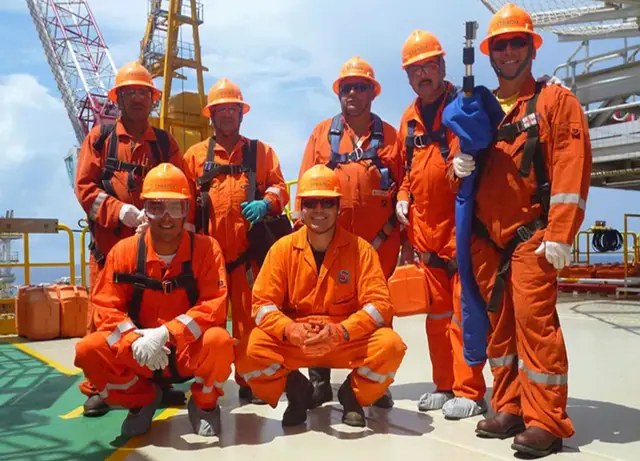 S-TRADIX crew in orange coveralls on an offshore deck